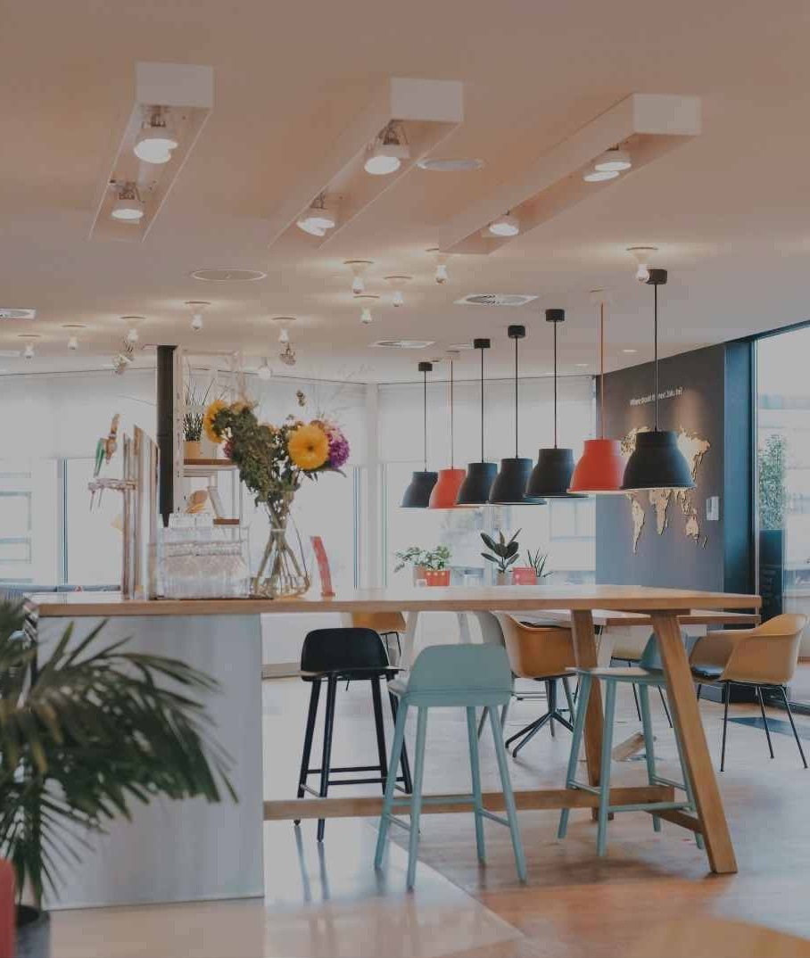 A warm, architectural Kiln co-working lounge with communal seating and pendant lighting